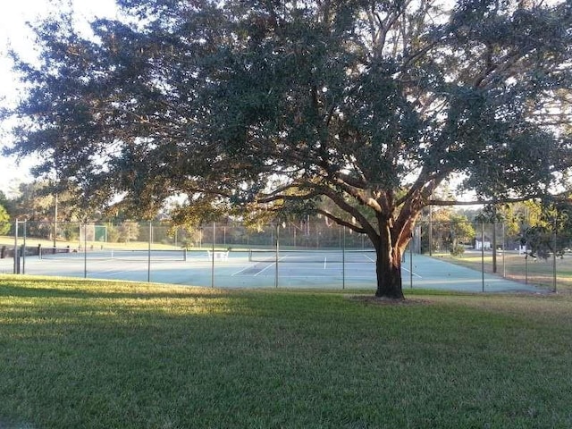 view of tennis court featuring a yard and fence