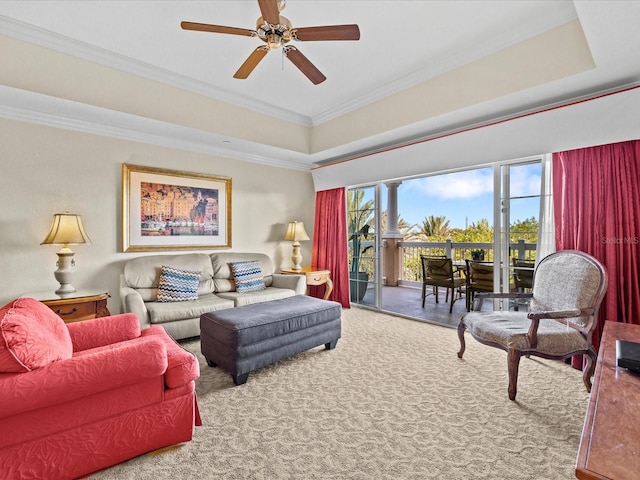living area featuring ceiling fan, carpet floors, crown molding, and a tray ceiling