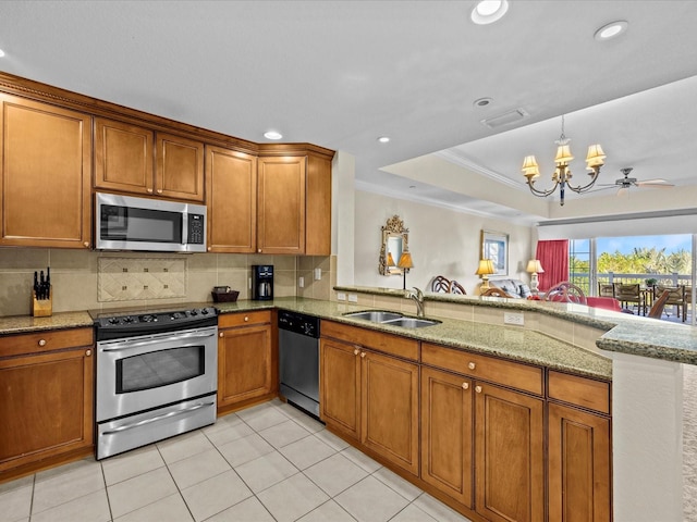 kitchen with light stone counters, sink, kitchen peninsula, stainless steel appliances, and ornamental molding