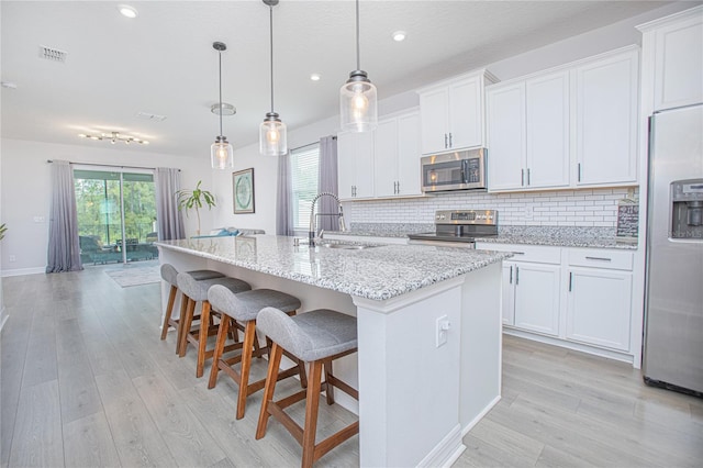 kitchen featuring a center island with sink, white cabinetry, and stainless steel appliances