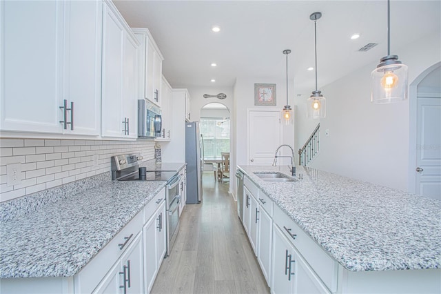 kitchen featuring light wood-type flooring, sink, white cabinetry, hanging light fixtures, and stainless steel appliances