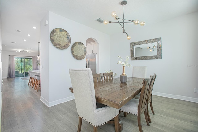 dining room with light wood-type flooring and a chandelier