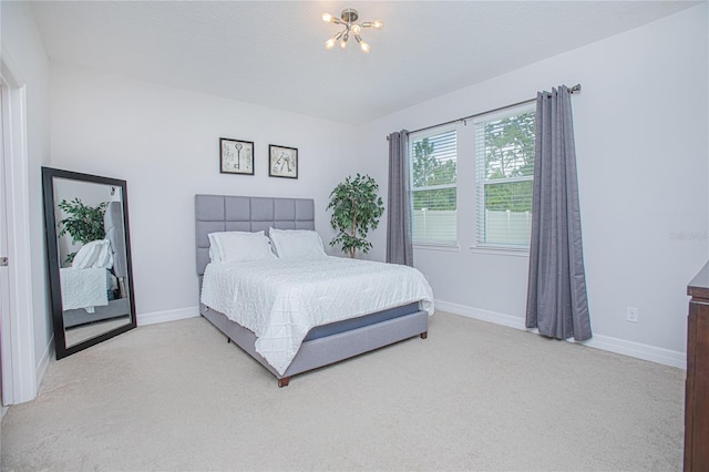 bedroom featuring light colored carpet and a chandelier