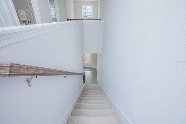 staircase with a chandelier and carpet floors