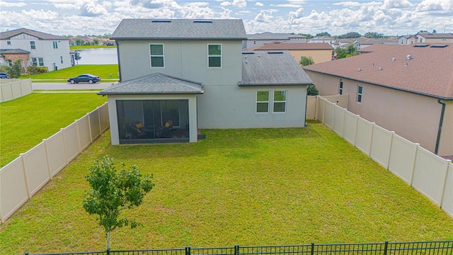 back of house with a lawn and a water view