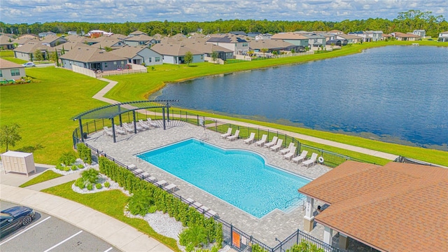 view of swimming pool featuring a patio, a water view, and a yard