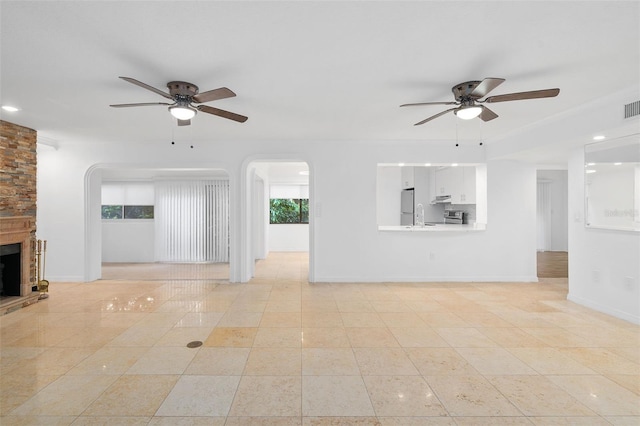 unfurnished living room with a fireplace, light tile patterned flooring, and ceiling fan