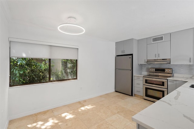 kitchen featuring light stone counters, gray cabinetry, stainless steel appliances, backsplash, and crown molding