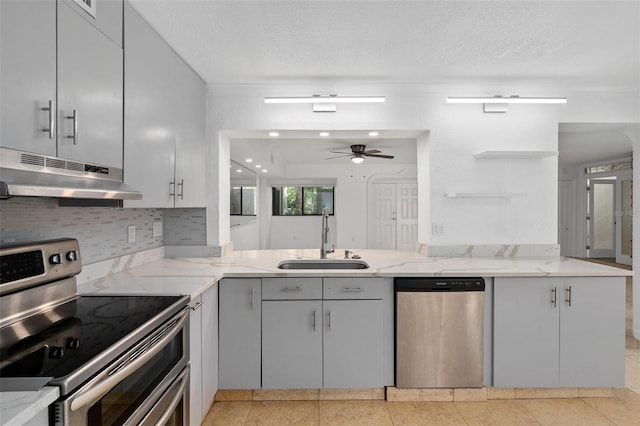 kitchen featuring appliances with stainless steel finishes, kitchen peninsula, sink, and light stone counters