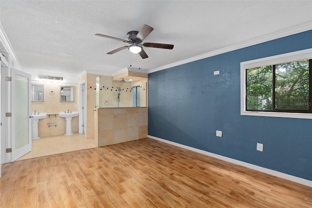 empty room featuring ceiling fan, sink, a textured ceiling, light hardwood / wood-style flooring, and crown molding