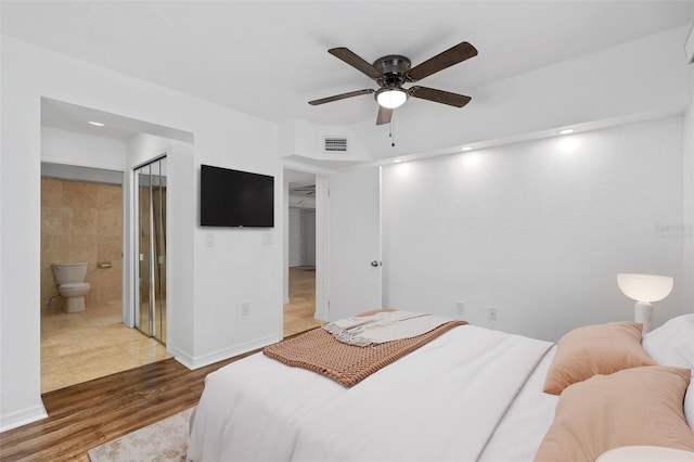 bedroom with ceiling fan, connected bathroom, wood-type flooring, a closet, and tile walls