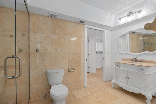 bathroom with tile patterned flooring, a textured ceiling, walk in shower, vanity, and toilet