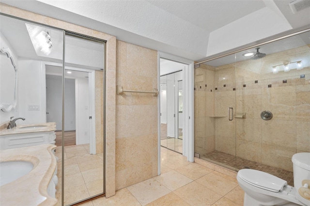 bathroom with vanity, walk in shower, a textured ceiling, toilet, and tile patterned floors