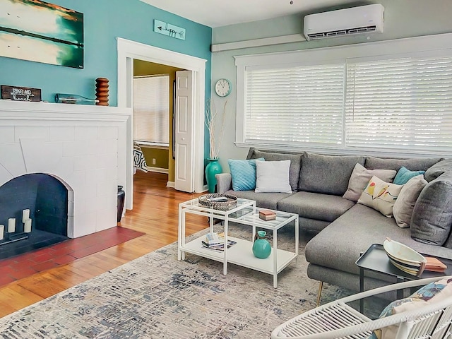 living room featuring wood-type flooring, a fireplace, and a wall mounted AC