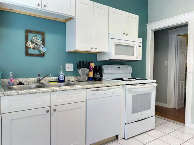 kitchen featuring white cabinets, white appliances, light tile patterned floors, and sink