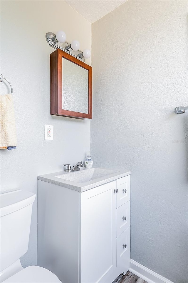 bathroom with wood-type flooring, vanity, and toilet