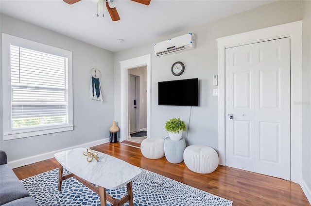 living room with ceiling fan, hardwood / wood-style flooring, and a wall unit AC