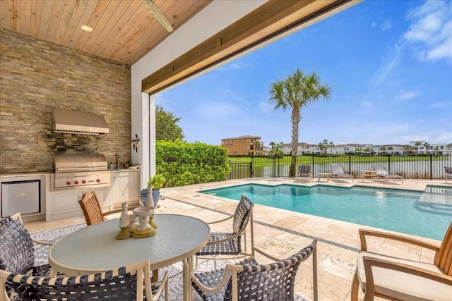 view of swimming pool featuring sink, an outdoor kitchen, a grill, and a patio