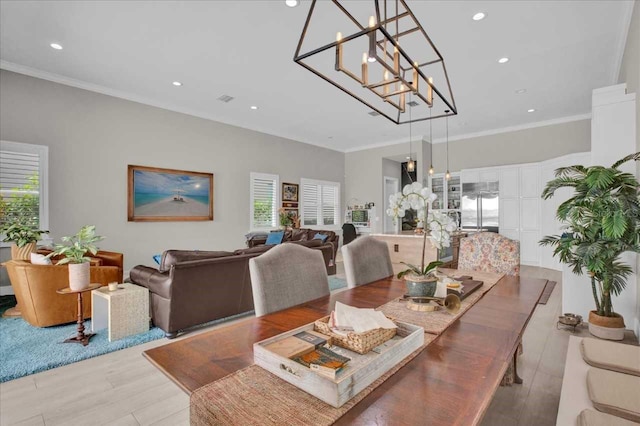 dining area featuring crown molding, a chandelier, light hardwood / wood-style flooring, and plenty of natural light