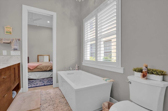 bathroom featuring hardwood / wood-style flooring, a washtub, ceiling fan, vanity, and toilet