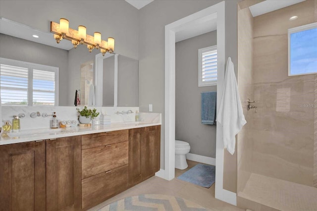 bathroom with a tile shower, vanity, toilet, and tile patterned floors