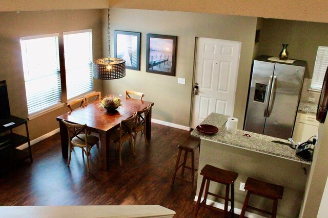 dining room with dark hardwood / wood-style floors, vaulted ceiling, and a wealth of natural light