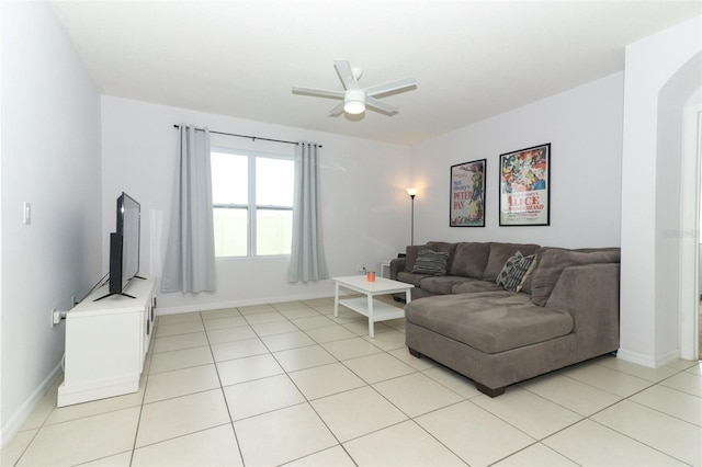 living area with arched walkways, baseboards, a ceiling fan, and light tile patterned floors