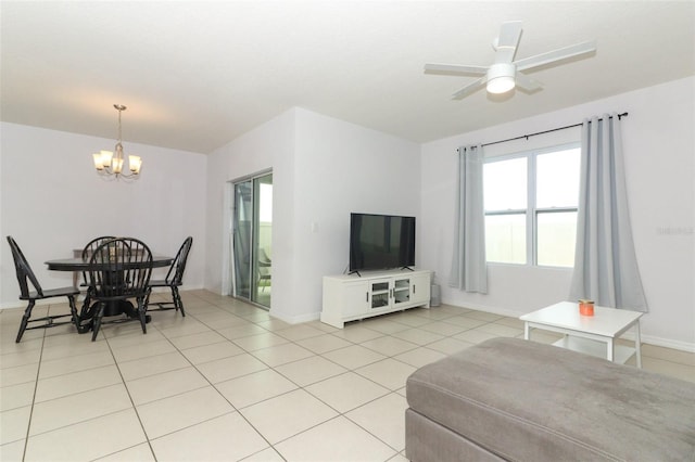 living room featuring baseboards, light tile patterned flooring, and ceiling fan with notable chandelier