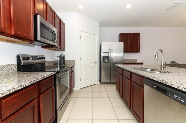 kitchen with stainless steel appliances, light stone countertops, sink, and light tile patterned flooring