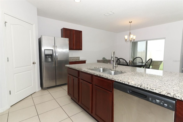 kitchen with light stone counters, stainless steel appliances, sink, and an inviting chandelier