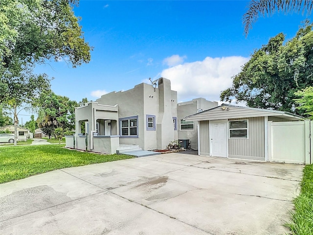 back of property featuring stucco siding, central air condition unit, and a lawn