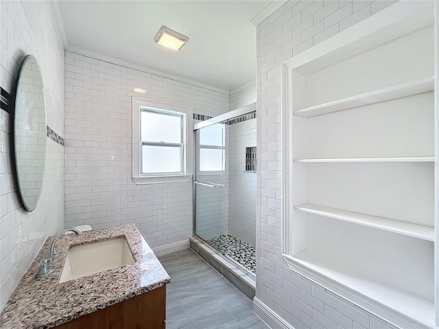 full bath with tile walls, a stall shower, and vanity
