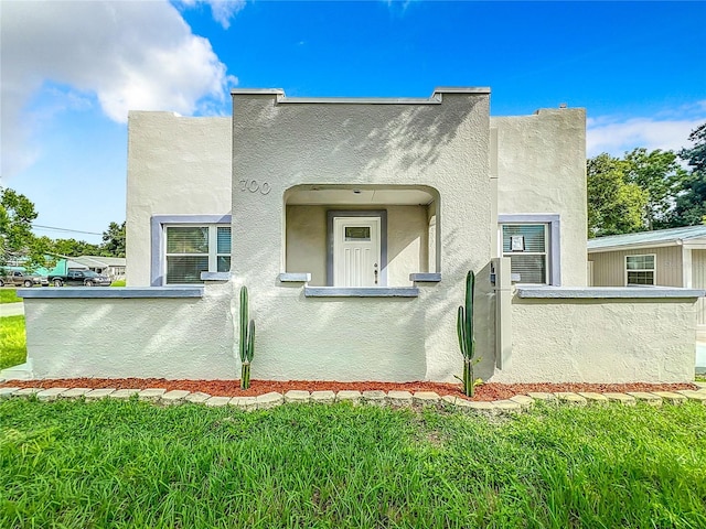 view of side of property featuring a lawn, stucco siding, and a fenced front yard