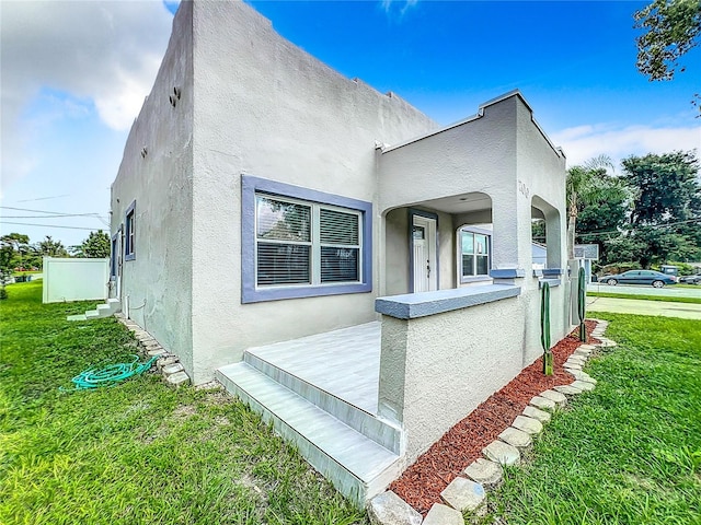 view of side of home with stucco siding and a yard