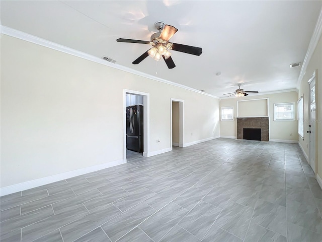 unfurnished living room featuring a ceiling fan, a brick fireplace, crown molding, and visible vents