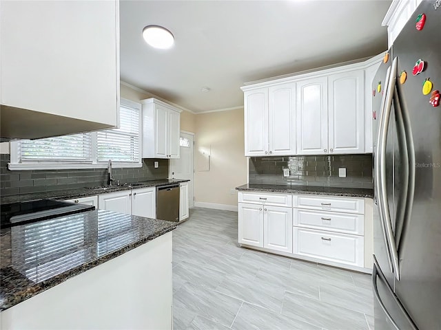 kitchen featuring backsplash, white cabinetry, dark stone countertops, stainless steel appliances, and ornamental molding