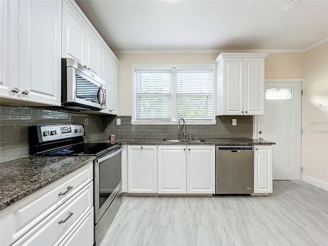 kitchen featuring sink, tasteful backsplash, white cabinetry, appliances with stainless steel finishes, and dark stone counters