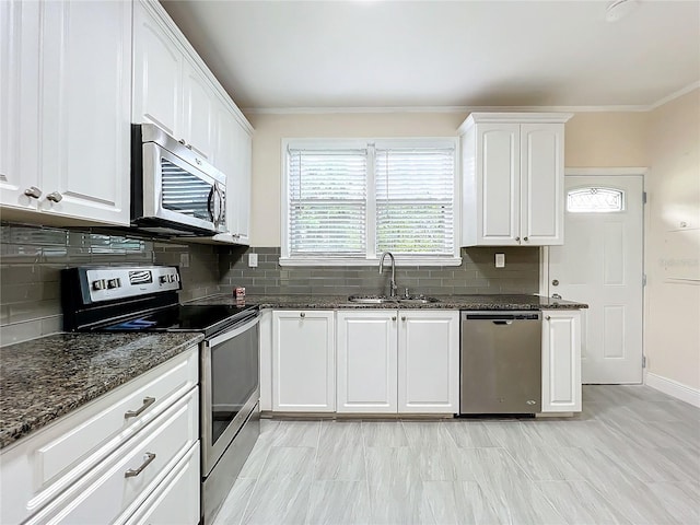 kitchen featuring dark stone countertops, white cabinetry, a sink, and appliances with stainless steel finishes