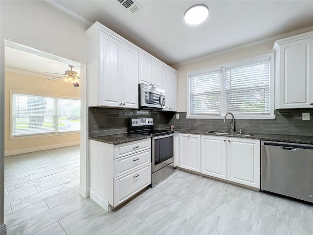 kitchen with visible vents, crown molding, appliances with stainless steel finishes, and dark stone counters