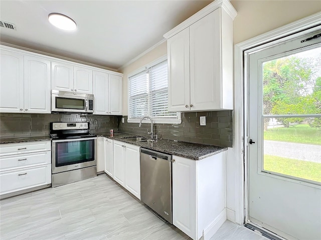 kitchen with a sink, white cabinetry, dark stone countertops, and appliances with stainless steel finishes