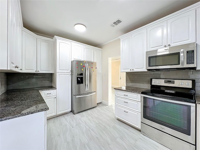 kitchen with dark stone countertops, stainless steel appliances, tasteful backsplash, and white cabinetry