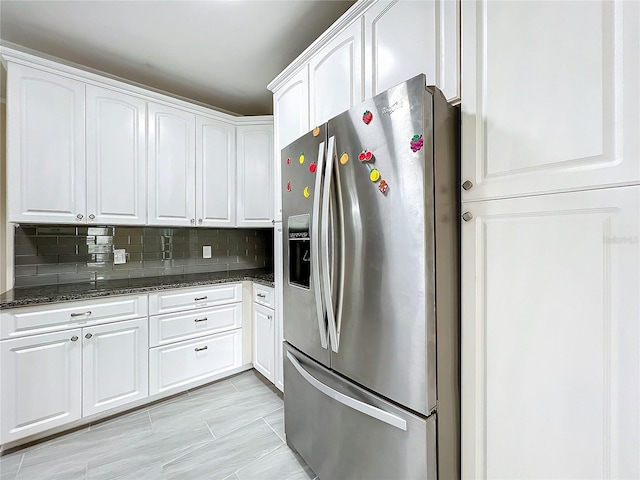 kitchen featuring dark stone counters, stainless steel refrigerator with ice dispenser, white cabinetry, and decorative backsplash