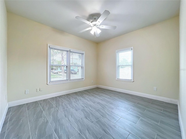 unfurnished room featuring baseboards, ceiling fan, and a wealth of natural light