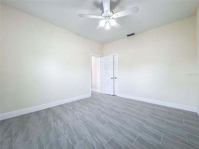 spare room with baseboards, visible vents, and ceiling fan