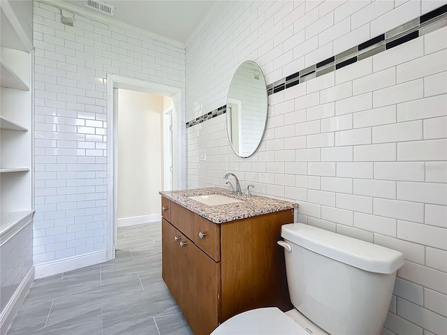 bathroom with tile walls, built in shelves, vanity, and toilet