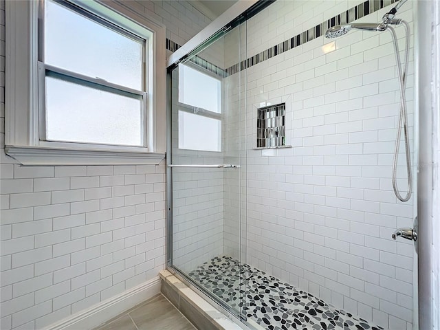 bathroom with a shower with door and tile patterned floors