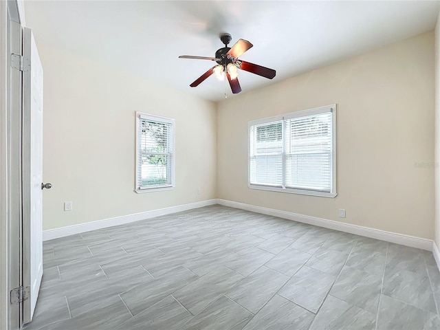 empty room featuring a ceiling fan and baseboards