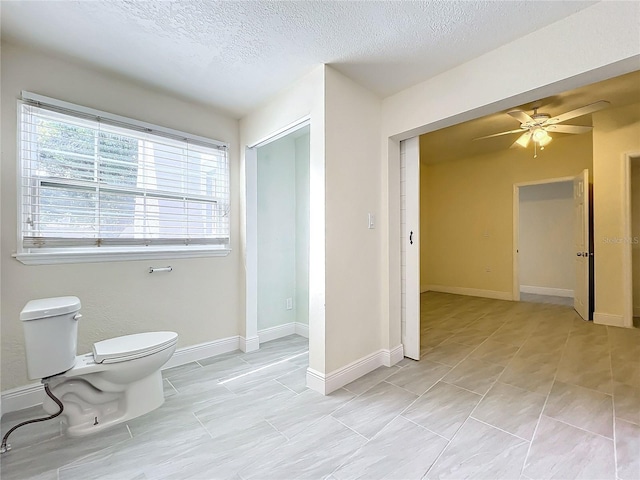 bathroom with a textured ceiling, ceiling fan, and toilet