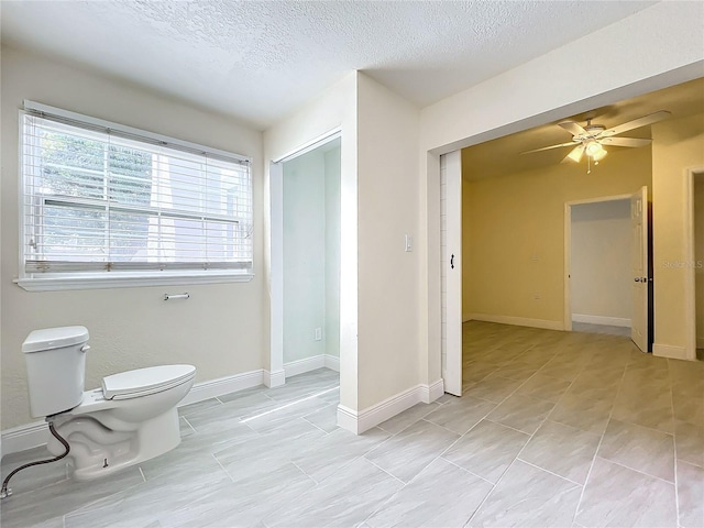 bathroom with a textured ceiling, baseboards, ceiling fan, and toilet
