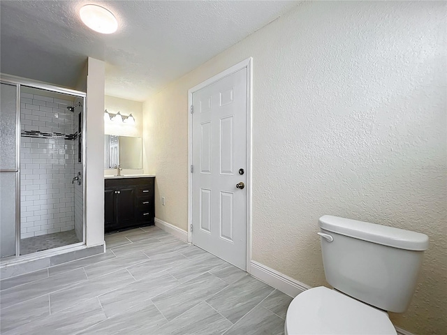 bathroom with a textured ceiling, walk in shower, vanity, and toilet